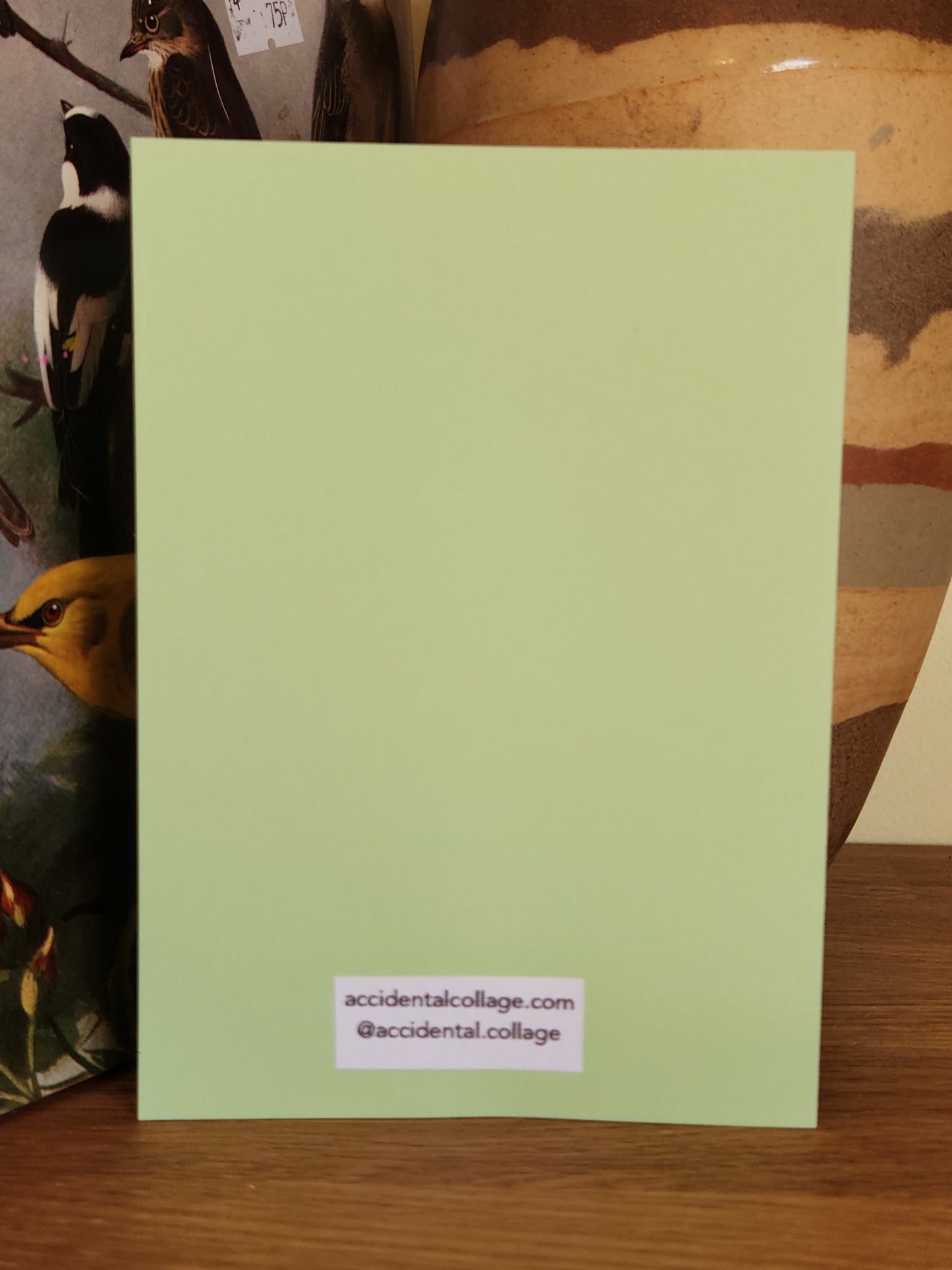 Back of a pale green, A6 greeting card with a small label at the bottom which reads: accidentalcollage.com, @accidental.collage