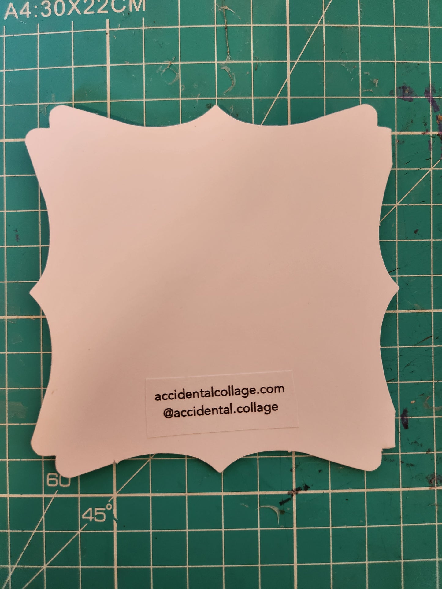 The back of a small white card with a decorative edge with a small label at the bottom which reads: accidentalcollage.com, @accidental.collage