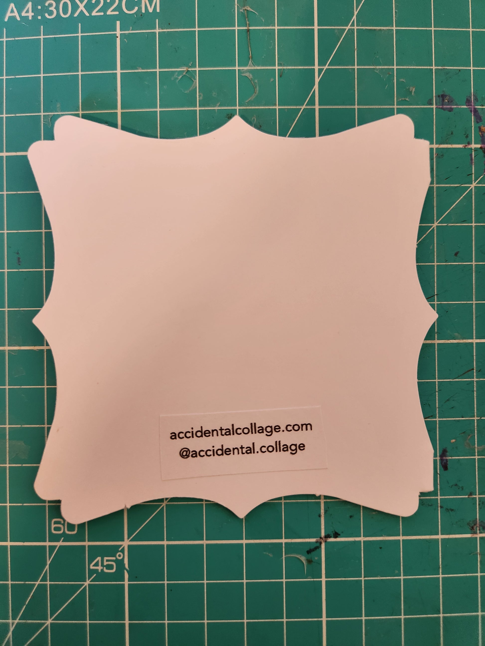 The back of a small white card with a decorative edge with a small label at the bottom which reads: accidentalcollage.com, @accidental.collage